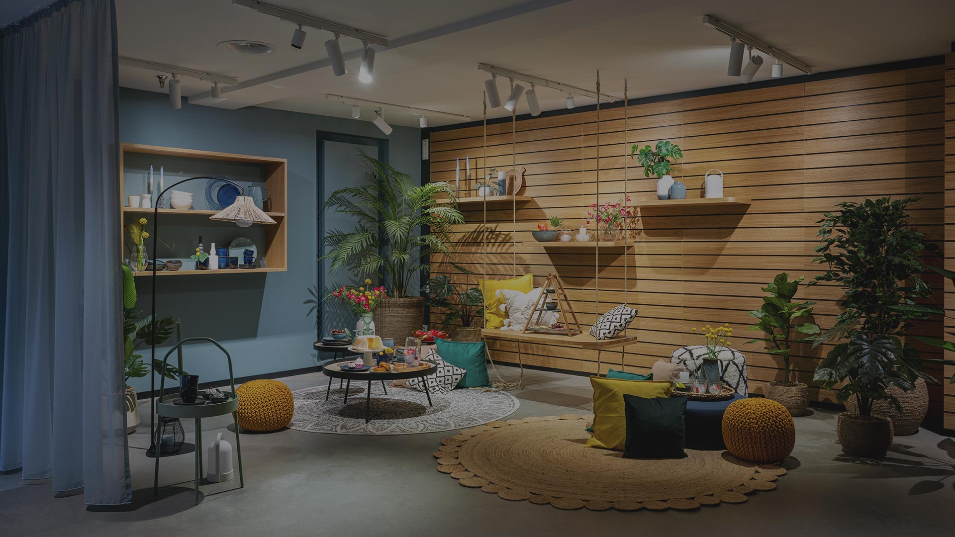 Modernes Raum mit Akzentwänden aus Holz, Zimmerpflanzen, einem Schaukelsitz, runden Teppichen, bunten Kissen und dekorativen Regalen mit verschiedenen Wohnaccessoires. Helle, gemütliche Atmosphäre.